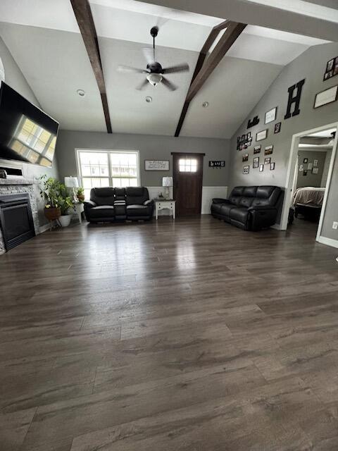 living room with a ceiling fan, lofted ceiling with beams, dark wood finished floors, and a fireplace