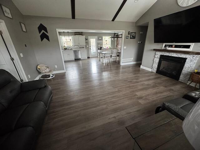 living area featuring baseboards, dark wood finished floors, lofted ceiling, and a fireplace