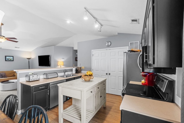 kitchen featuring lofted ceiling, open floor plan, light countertops, a sink, and stainless steel appliances