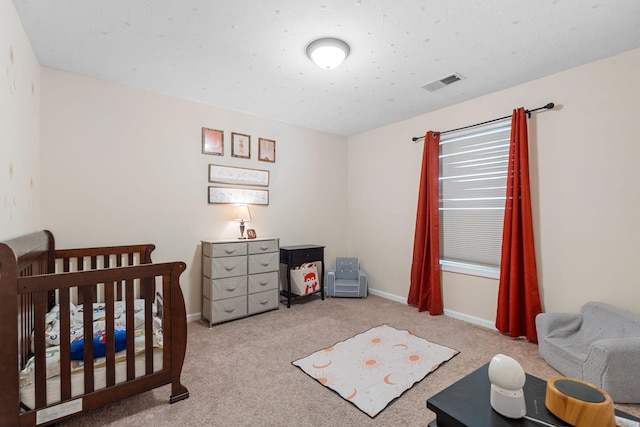bedroom featuring carpet floors, a nursery area, baseboards, and visible vents