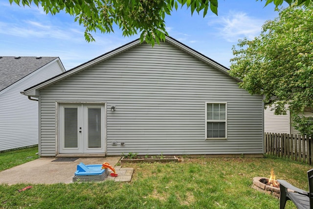 back of property featuring fence, french doors, a patio area, a lawn, and a fire pit