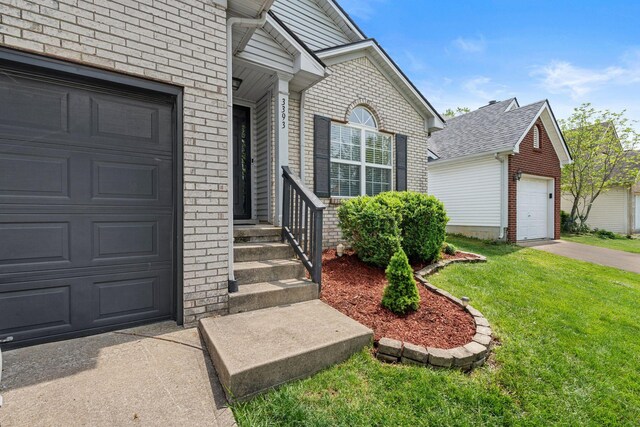property entrance with a lawn, a garage, and brick siding