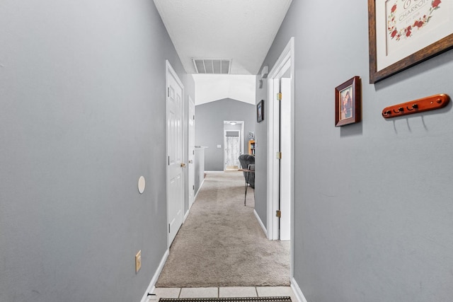 hallway with baseboards, carpet, vaulted ceiling, and visible vents