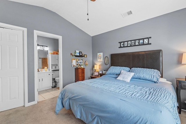 bedroom featuring visible vents, vaulted ceiling, light tile patterned floors, ensuite bathroom, and light carpet