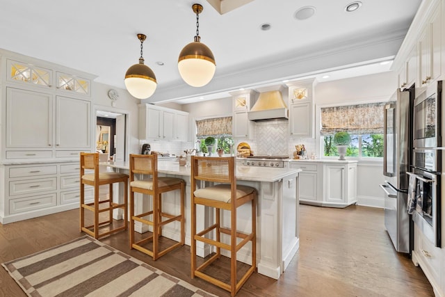 kitchen featuring appliances with stainless steel finishes, a kitchen breakfast bar, backsplash, and custom exhaust hood