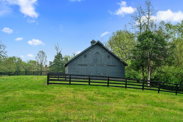 view of side of property featuring fence, a barn, an outdoor structure, and a yard