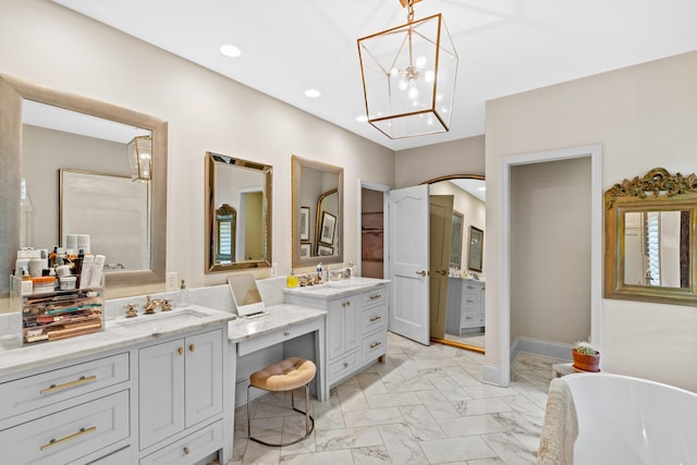full bath with a freestanding tub, vanity, marble finish floor, an inviting chandelier, and recessed lighting