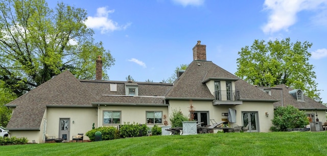 rear view of property featuring a lawn, roof with shingles, stucco siding, and french doors
