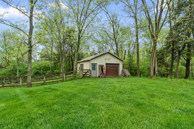 view of yard featuring fence, an outdoor structure, and a garage