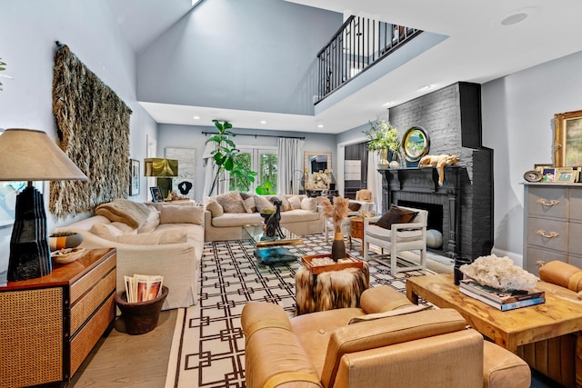 living room with a fireplace, recessed lighting, wood finished floors, and a towering ceiling