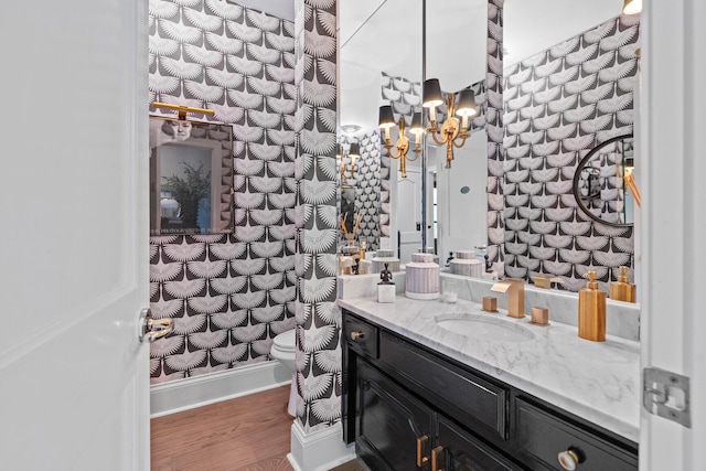 bathroom with toilet, a chandelier, wood finished floors, and vanity