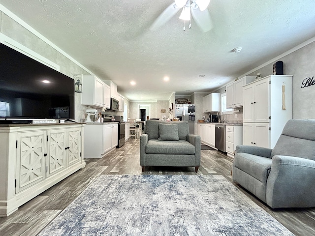 living room featuring a textured ceiling, ceiling fan, and wood finished floors