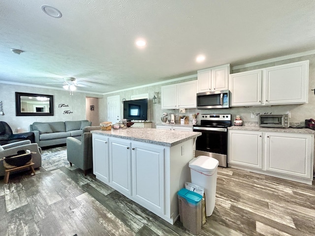 kitchen with a kitchen island, wood finished floors, light countertops, stainless steel appliances, and white cabinetry