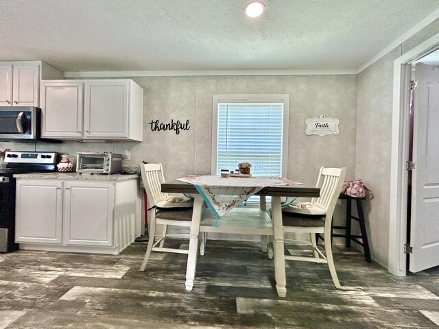 dining room featuring a toaster, a textured ceiling, crown molding, and wood finished floors