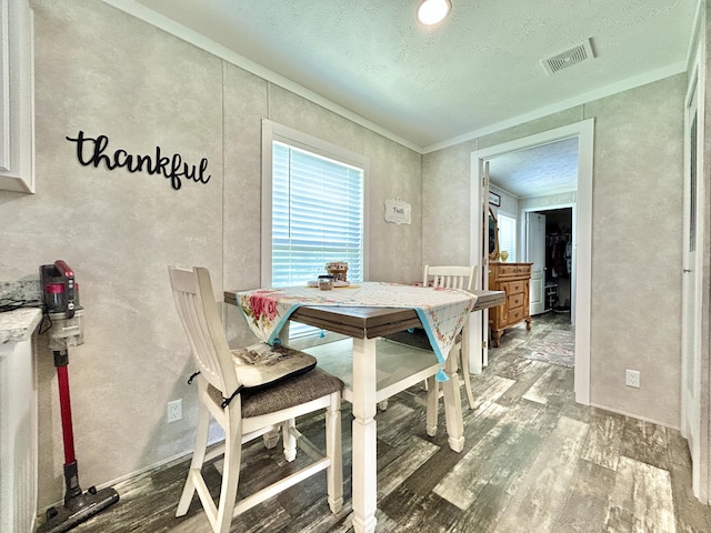dining space with visible vents, ornamental molding, a textured ceiling, and wood finished floors