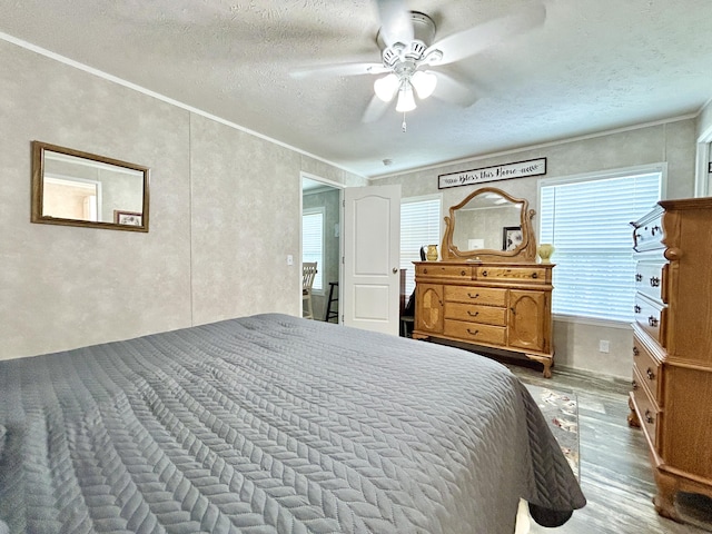 bedroom with a textured ceiling, ceiling fan, and wood finished floors