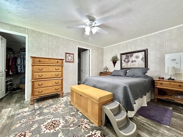 bedroom with a closet, a walk in closet, a textured ceiling, and wood finished floors