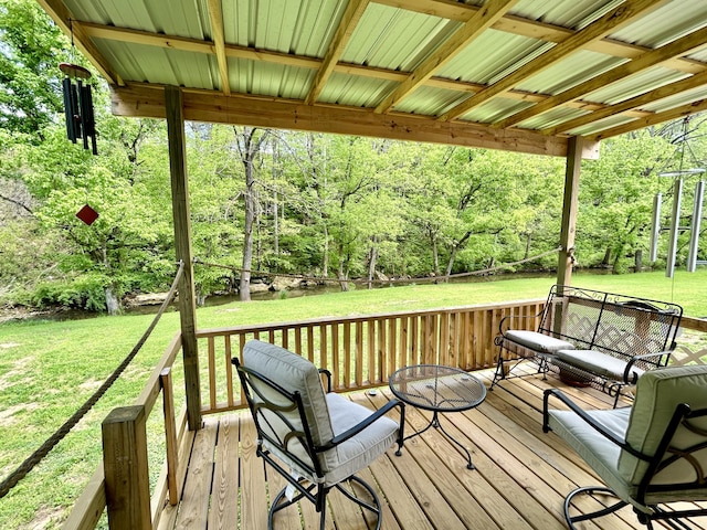 wooden terrace with a lawn and a view of trees