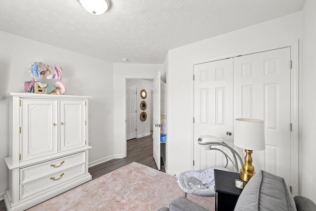bedroom with baseboards, a closet, dark wood-style floors, and a textured ceiling