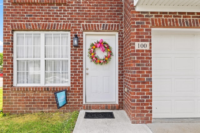 doorway to property with a garage and brick siding