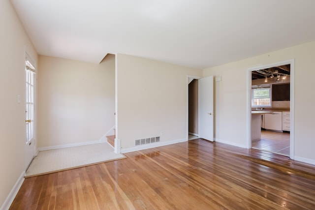 unfurnished room with stairs, baseboards, visible vents, and light wood-style floors