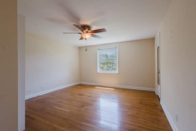 spare room featuring baseboards, wood finished floors, and a ceiling fan