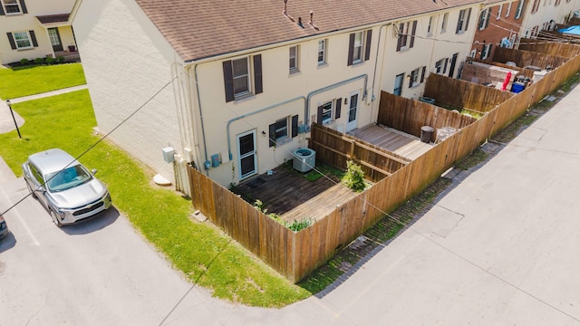 back of property featuring a shingled roof, stucco siding, fence private yard, and central air condition unit