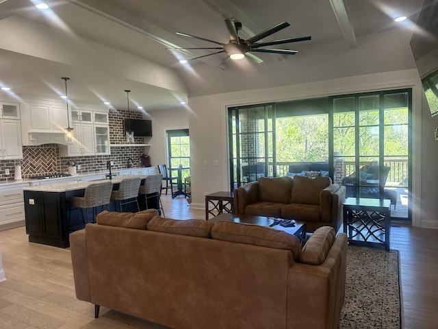 living area featuring baseboards, ceiling fan, vaulted ceiling, and light wood-type flooring