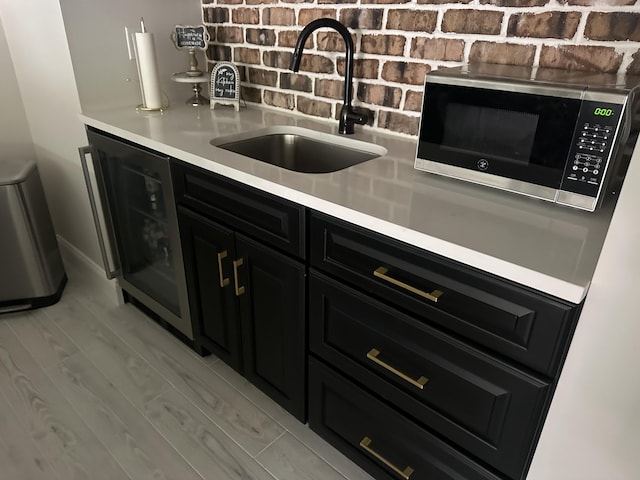 bar featuring stainless steel microwave, tasteful backsplash, a sink, and wine cooler