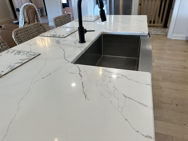details with light stone counters, a sink, and light wood-style flooring