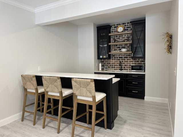 bar with backsplash, wet bar, a sink, baseboards, and ornamental molding