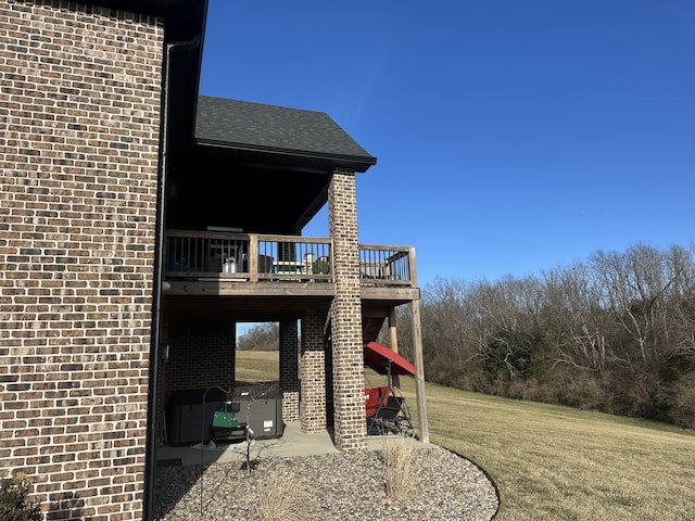 view of property exterior featuring a yard, a deck, brick siding, and a patio area