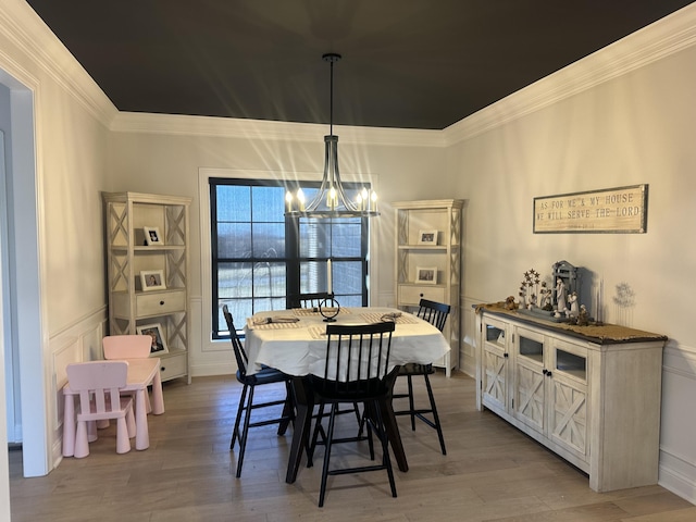 dining space with an inviting chandelier, ornamental molding, and light wood-style flooring