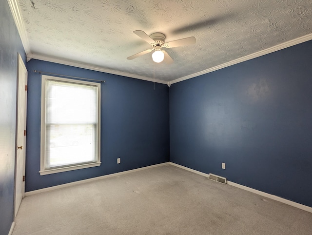 carpeted spare room featuring baseboards, ornamental molding, a ceiling fan, and visible vents