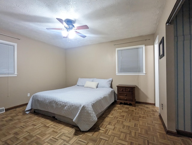 bedroom featuring baseboards, a textured ceiling, ceiling fan, and visible vents