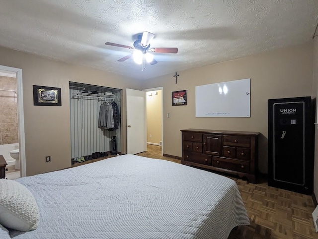 bedroom with a closet, a textured ceiling, ceiling fan, and ensuite bath