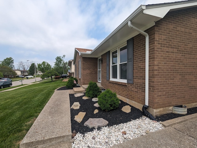 view of home's exterior with a lawn and brick siding