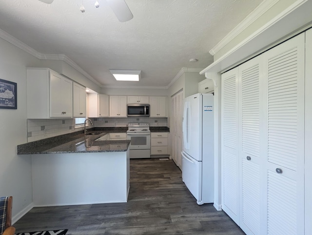 kitchen featuring a sink, a peninsula, white cabinets, and white appliances