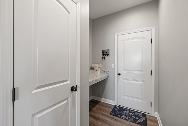 doorway with baseboards and dark wood-type flooring