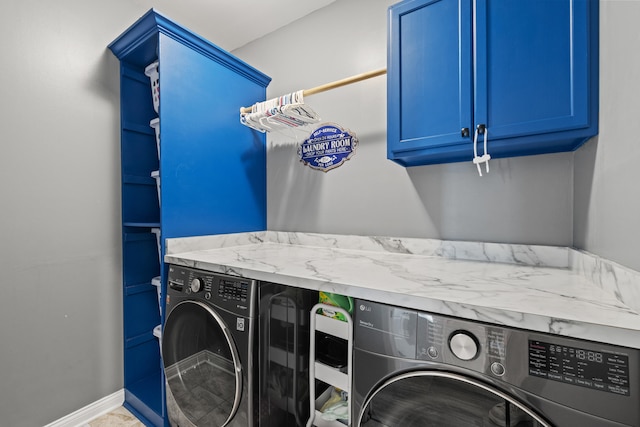 clothes washing area featuring baseboards, cabinet space, and washer and dryer