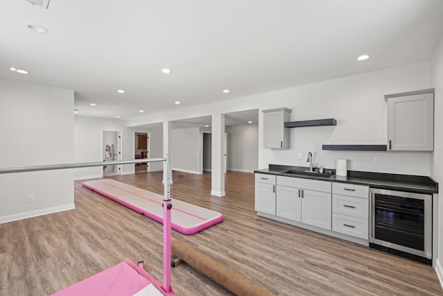 bar featuring a sink, recessed lighting, wet bar, light wood-type flooring, and wine cooler
