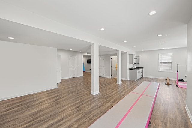 interior space with baseboards, recessed lighting, a sink, and wood finished floors