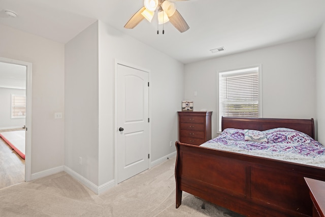 bedroom featuring baseboards, ceiling fan, light carpet, and visible vents