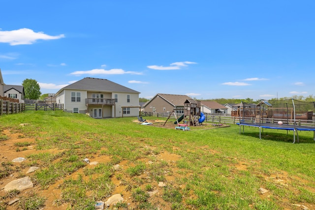 view of yard with a fenced backyard, a trampoline, a playground, and a balcony