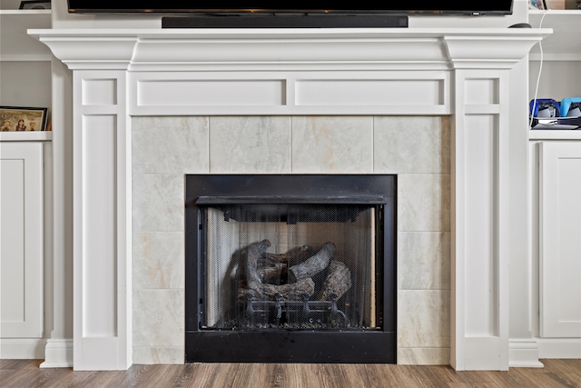 interior details featuring a tiled fireplace and wood finished floors