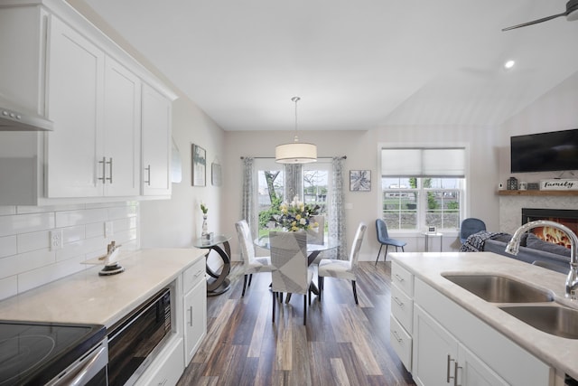 kitchen with dark wood-style flooring, a warm lit fireplace, a sink, light countertops, and open floor plan