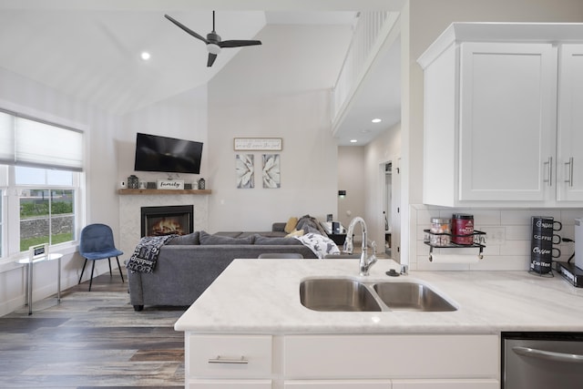 kitchen with white cabinets, a sink, a ceiling fan, open floor plan, and stainless steel dishwasher