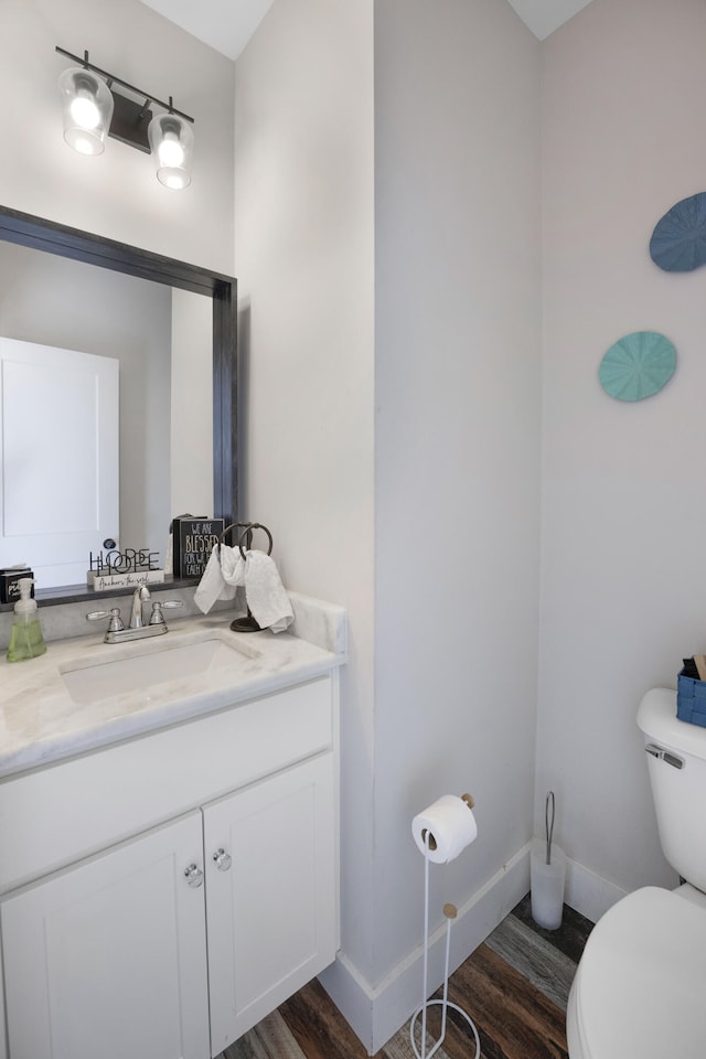 bathroom with vanity, baseboards, toilet, and wood finished floors