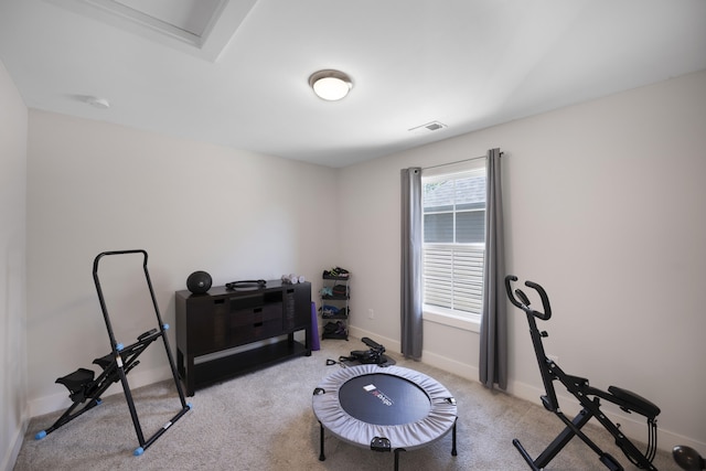 workout area with baseboards, visible vents, and light carpet