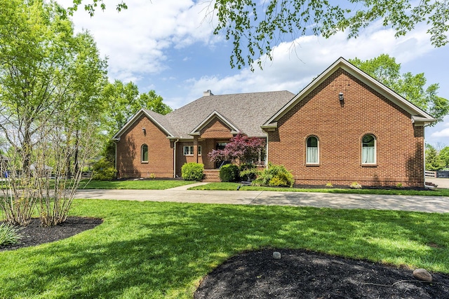 view of front of property featuring brick siding, a chimney, and a front yard
